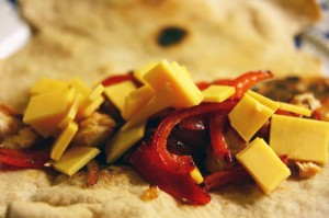 Fladbrød med fajita af kylling, rød peber, løg og lagret cheddar
